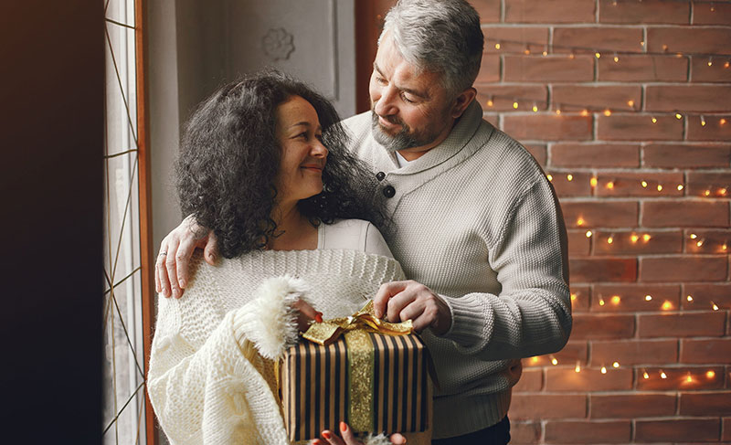 Senior couple with gifts near the christmas tree
