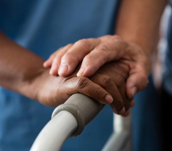 Caregiver touching patient's hand at MetroHealth Inc.